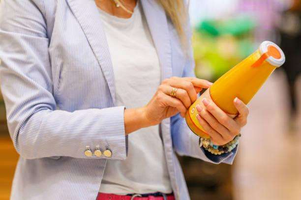 Woman examines nutritional label on orange juice bottle